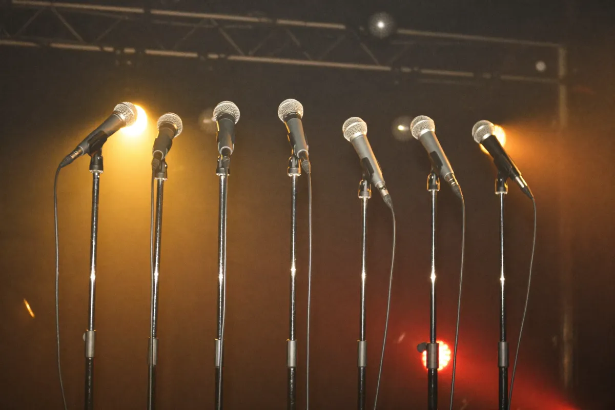 A row of microphones on a lit stage